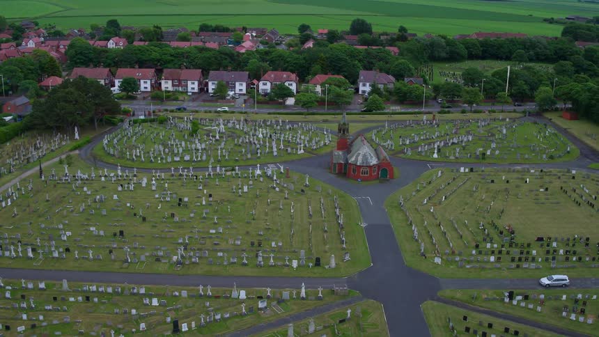 Cars drive on the road near this cemetery