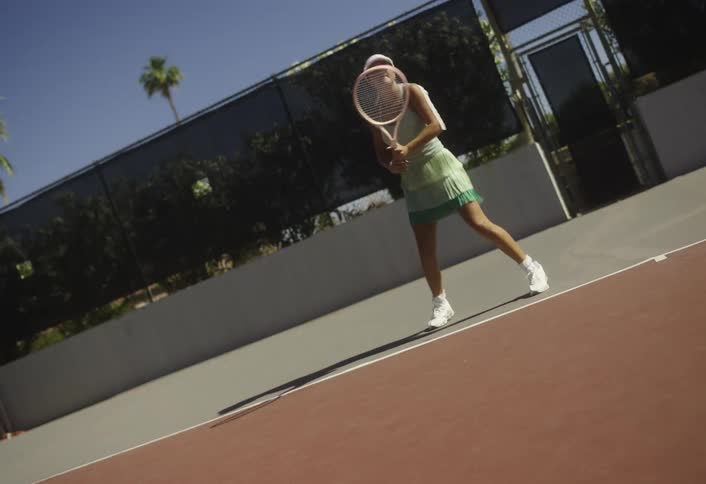 Woman on a court playing tennis outdoors