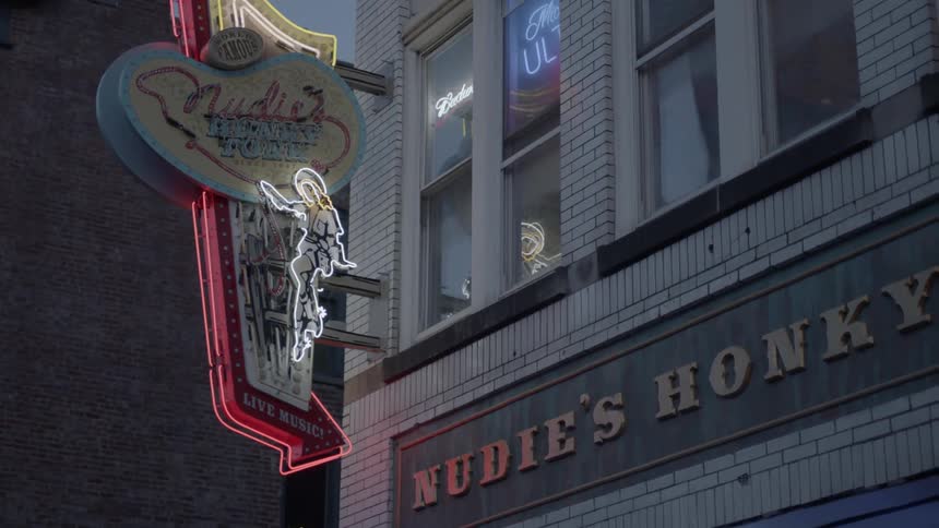 Neon sign comes into focus outside of a building