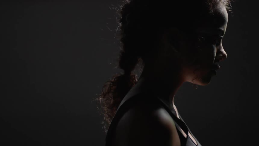 A woman slowly raises her head in the dark