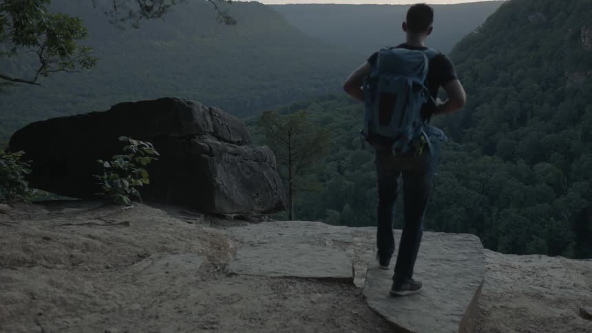 A man hikes toward a ledge and takes in a view