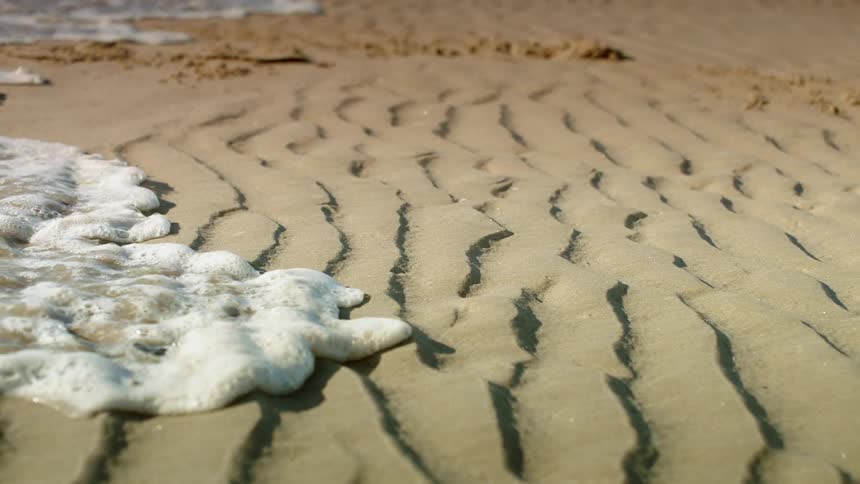 Foamy water washes ashore on a beach