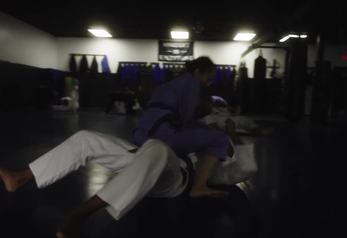 Martial artists grapple on a gym mat during a brazilian jiujitsu training session