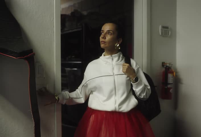 Woman in a white skirt and jacket turning on the light in a room of the house