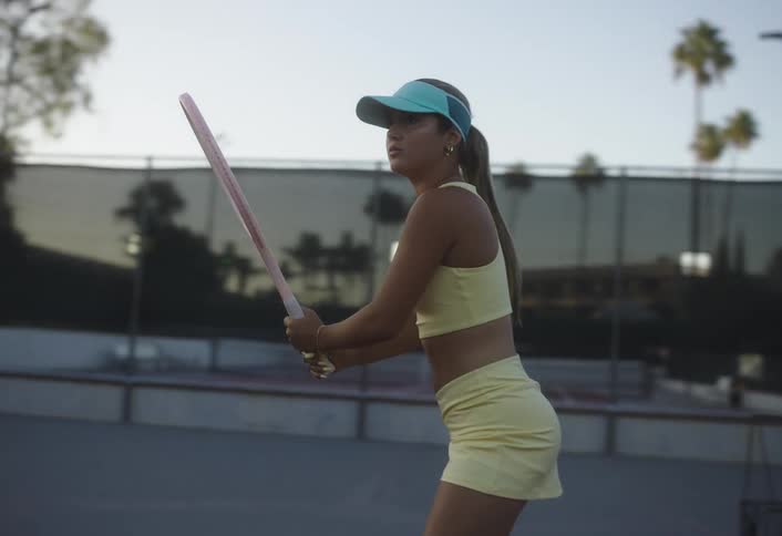 Female tennis player plays tennis at an outdoor court at sunset
