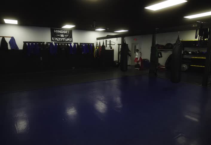 A woman walks into the gym and stretches