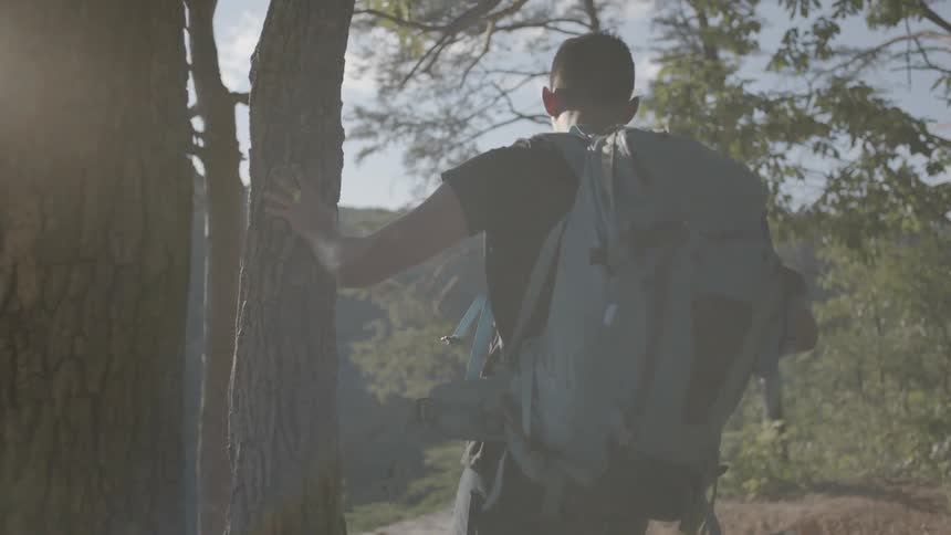 Man wearing a backpack hikes through the woods