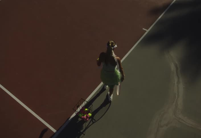 A woman practices her tennis serve at the court