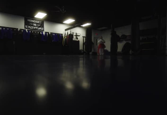 A woman enters the gym and turns the lights on before stretching