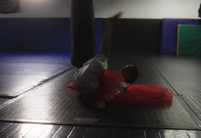Woman wearing a gauzy outfit exercises on the floor in a gym