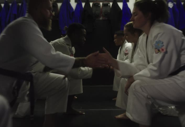 Martial arts trainees line up shaking hands with a writing on the wall that says mindset is everything