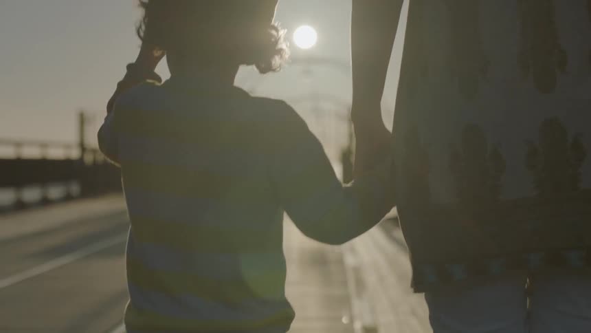 A woman and child walk hand in hand along a pier