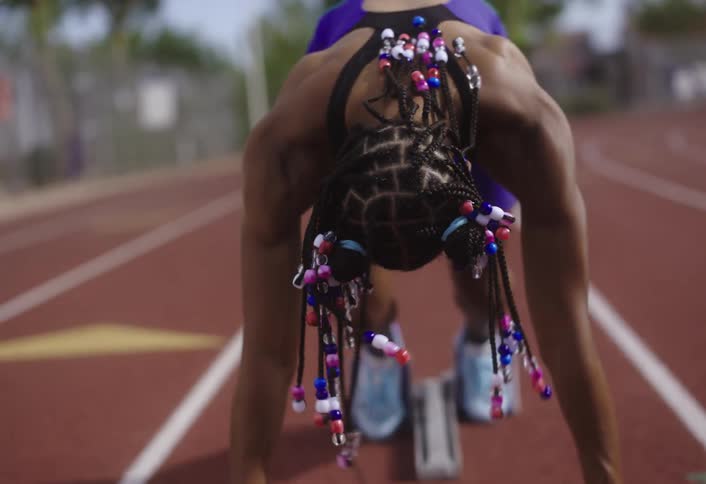 A black lady gets set for a track race at daytime