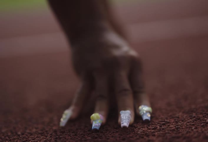 A runner has their hand on the track