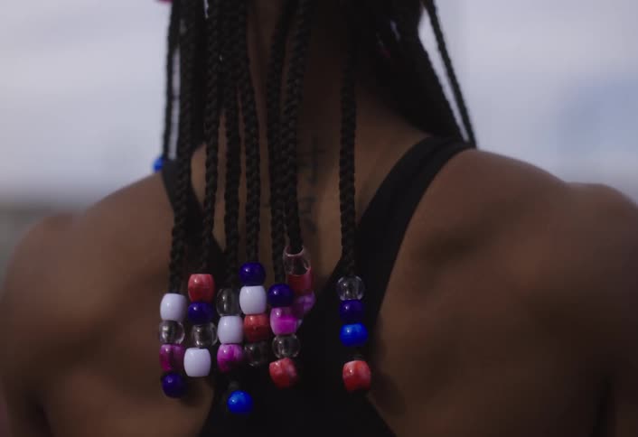 Back of a woman with dreadlocks stretching her body