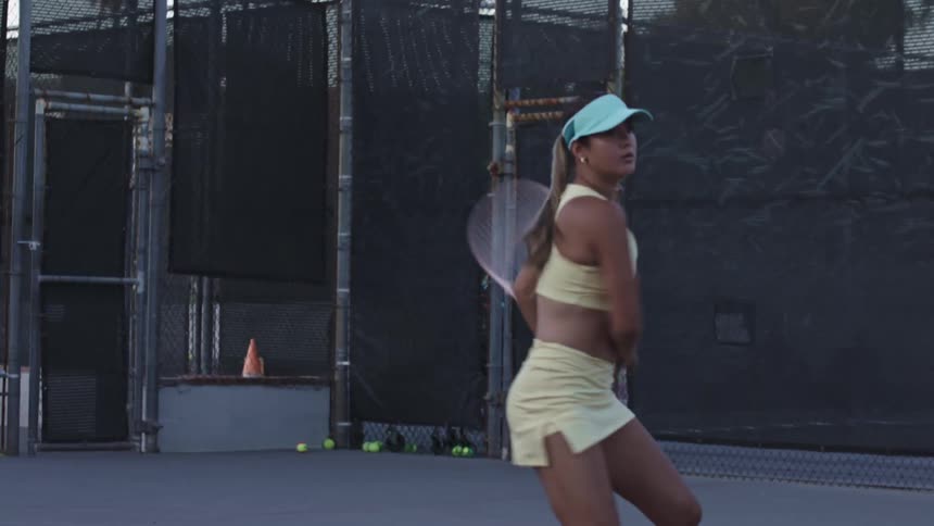 Female tennis player smashes the ball across the outdoor court
