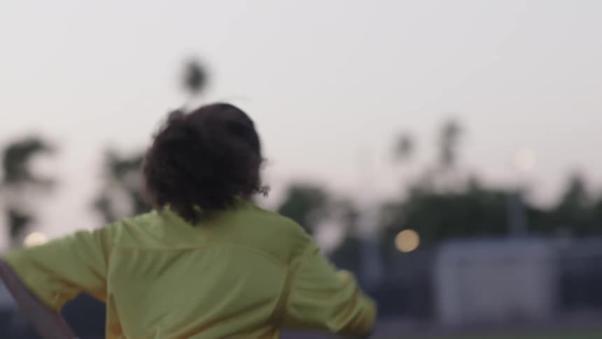 A young female athlete works out in the field at sunrise wearing a yellow jersey