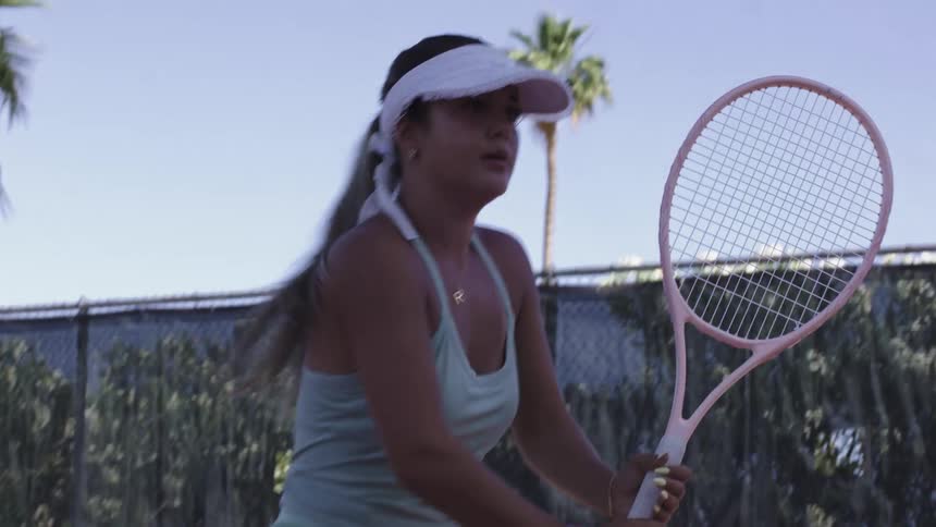 A woman swings the racket while playing tennis
