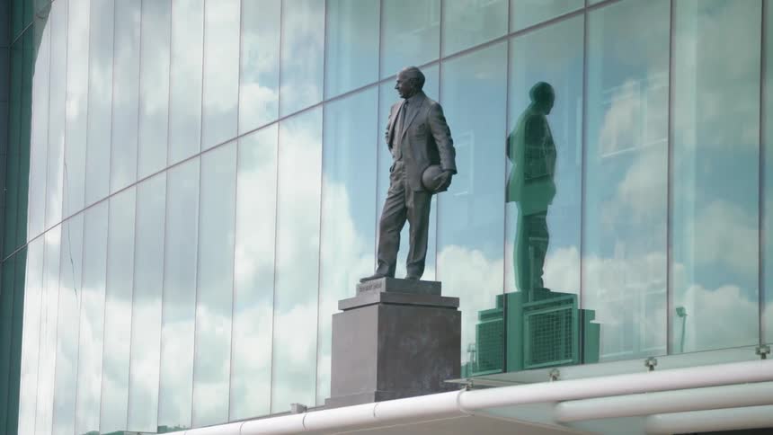 A basketball player statue stands in front of a glass building