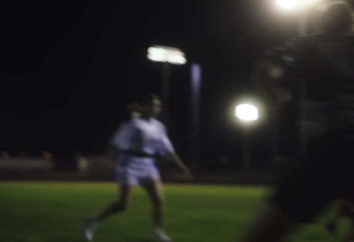 Women on a grass field at night playing american football