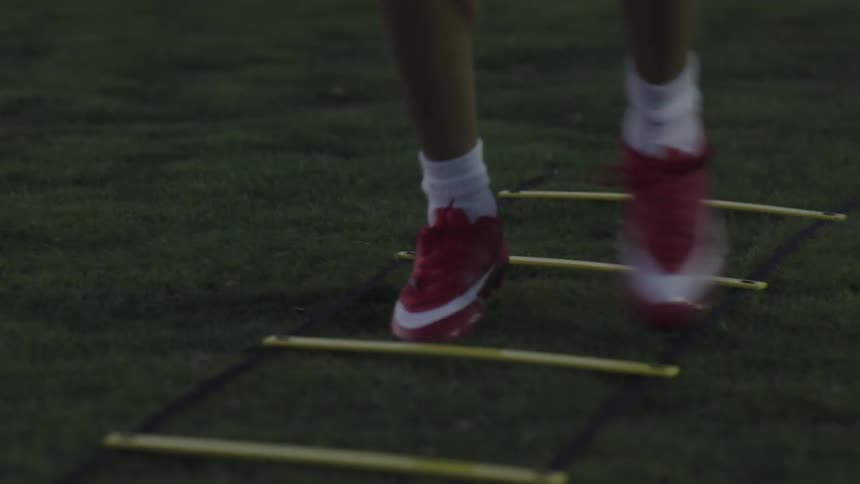 Legs of a person wearing soccer shoes doing educational warmups on the grass