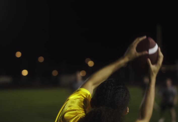 A woman catches the football at night