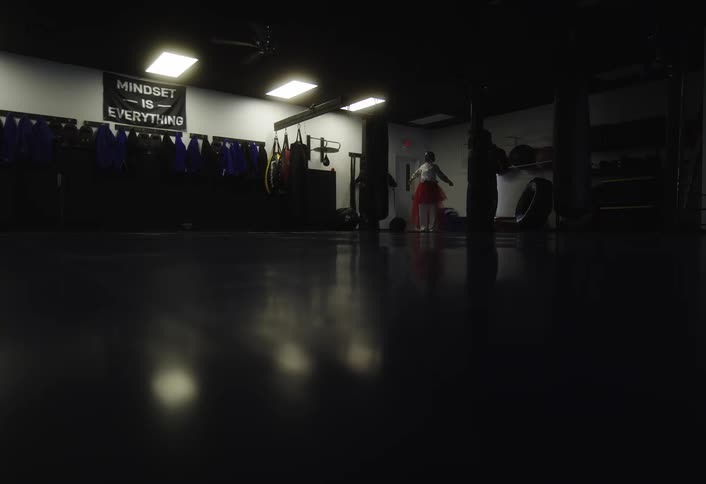 A woman enters the gym and stretches