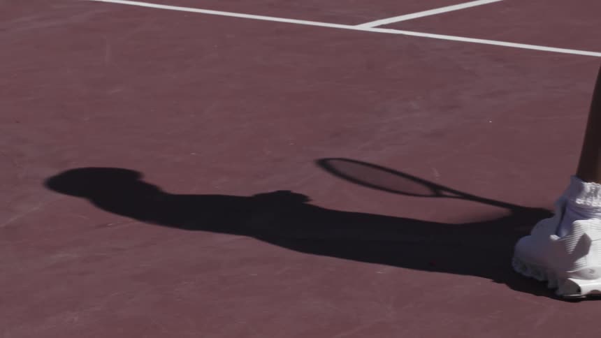 A woman bounces the ball on the tennis court