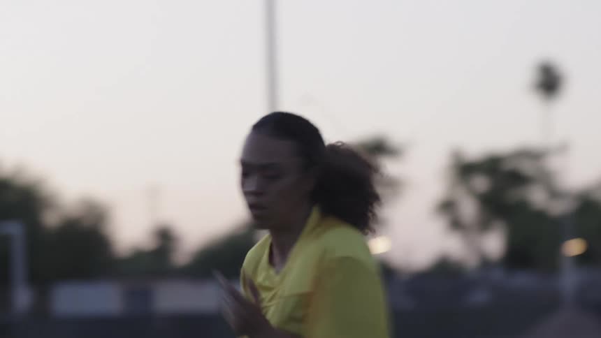 An athlete trains in a field at sunrise wearing a yellow jersey