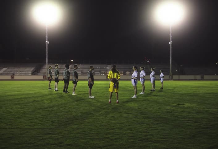 Football players stand in a v shape on the field