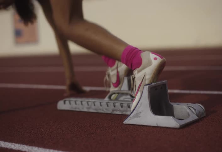 Woman positioning herself on a running track and speeding away