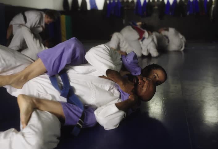 Two people grapple on the mat in a brazilian jiujitsu training session