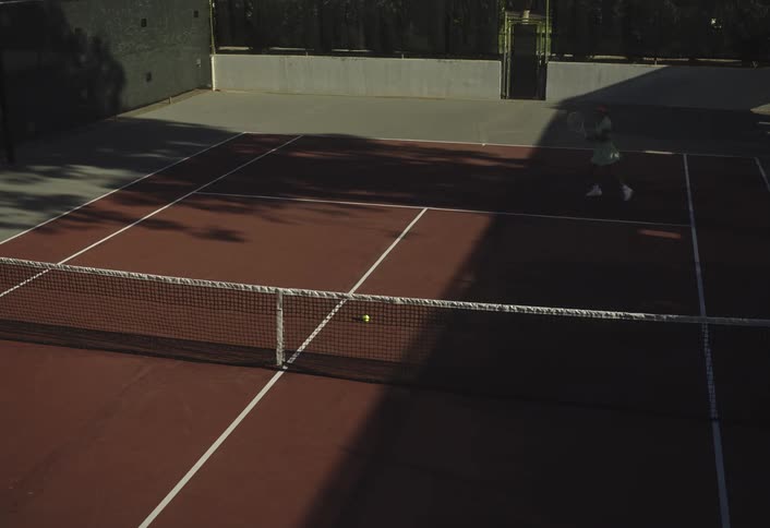 A woman playing tennis on a court hitting balls using her racket