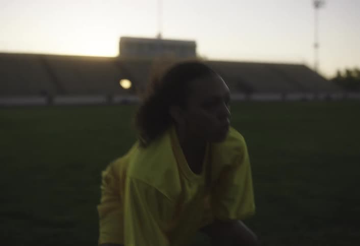 A female athlete trains on a football field at sundown