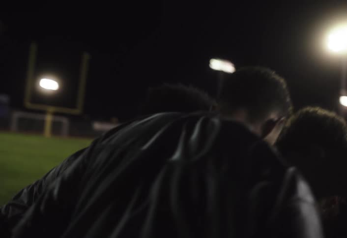 A football team celebrates with excitement cheering each other on the pitch under the night lights