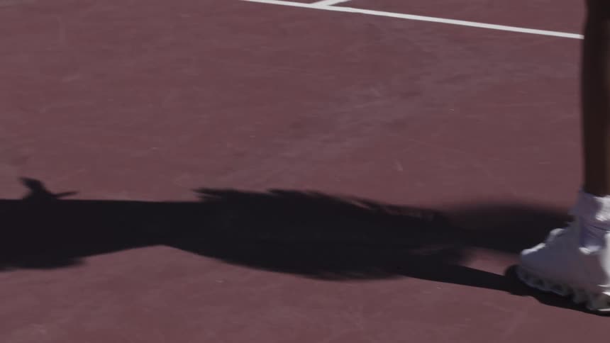 The tennis player gives off a shadow while swinging her racket