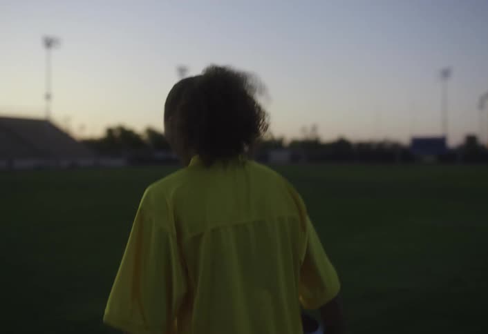 A woman walks on the field with a football