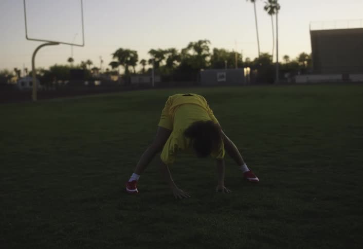 The woman is stretching on the football field