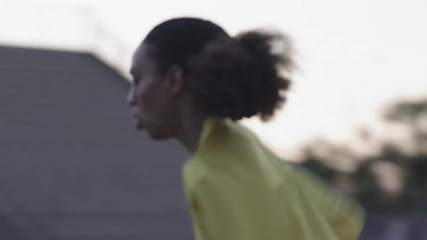 A woman training hurdle running on a football field in a stadium
