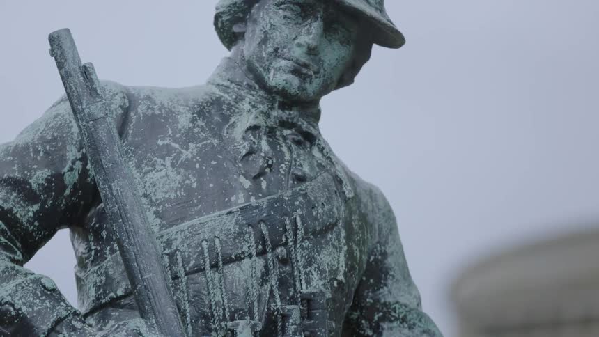 A bronze statue is of a man holding a rifle