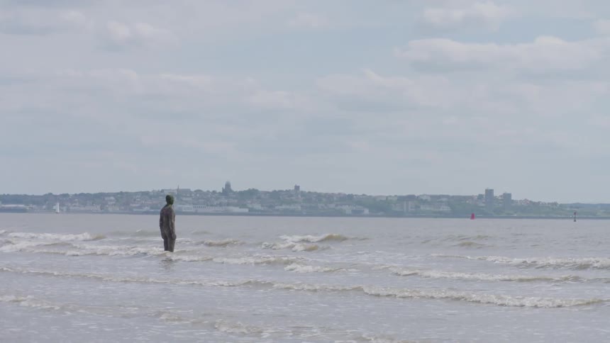 Statue of standing person in shallow ocean water