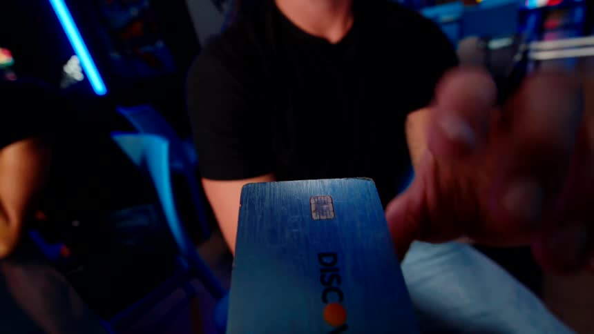 A person hands over their credit card in the arcade