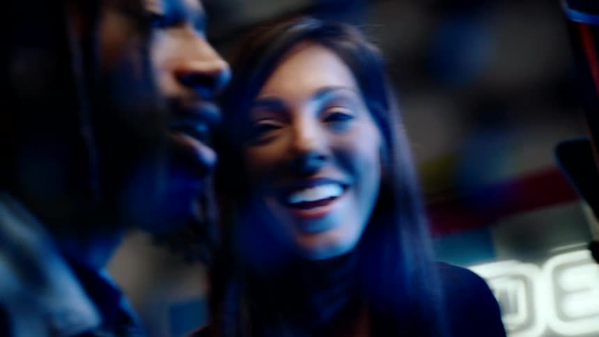 A man and a woman at an arcade game smile and enjoy a good time together