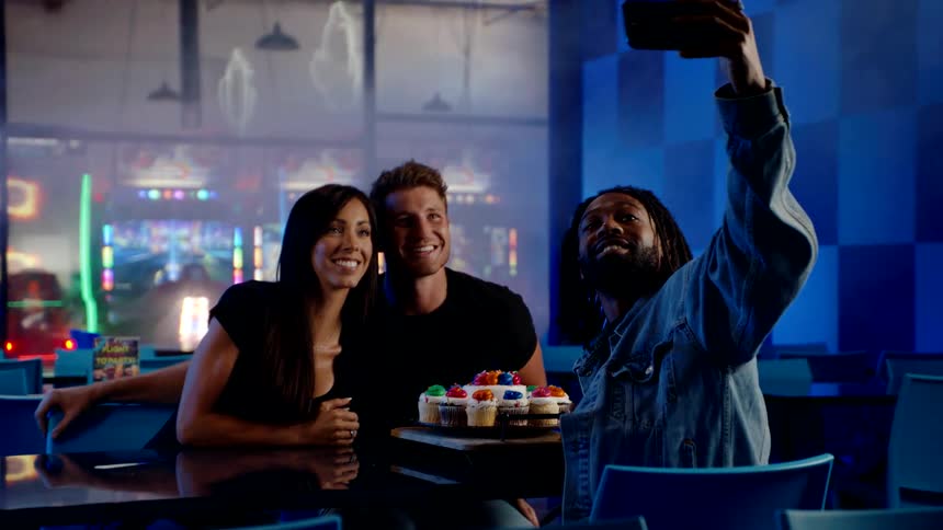 Group of friends take a selfie while seated at a table in a restaurant at night
