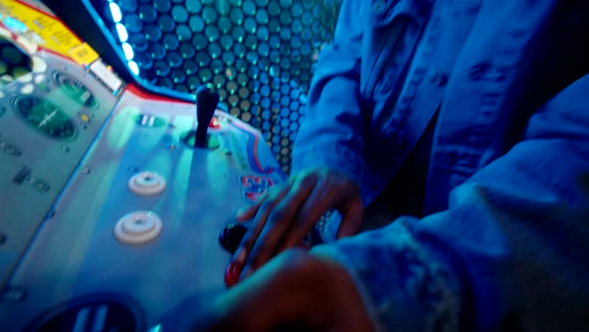 A man and a woman playing an arcade game pressing buttons and they are happy
