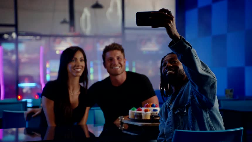 Three friends take a selfie while celebrating indoors with cupcakes