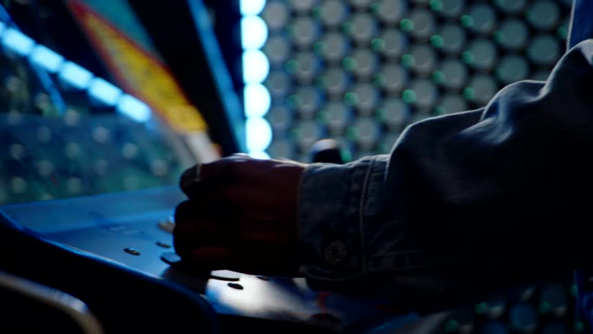 The man moves the joystick fast on the arcade cabinet