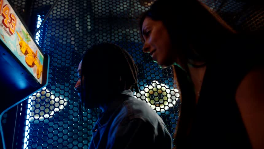A woman is watching a man play a video game
