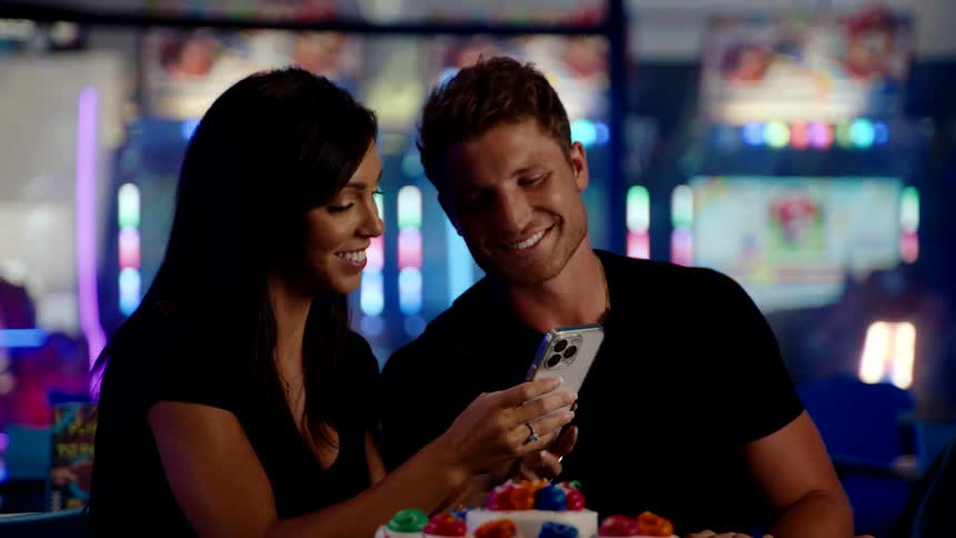A group of friends takes a photo of colorful cupcakes at an arcade table
