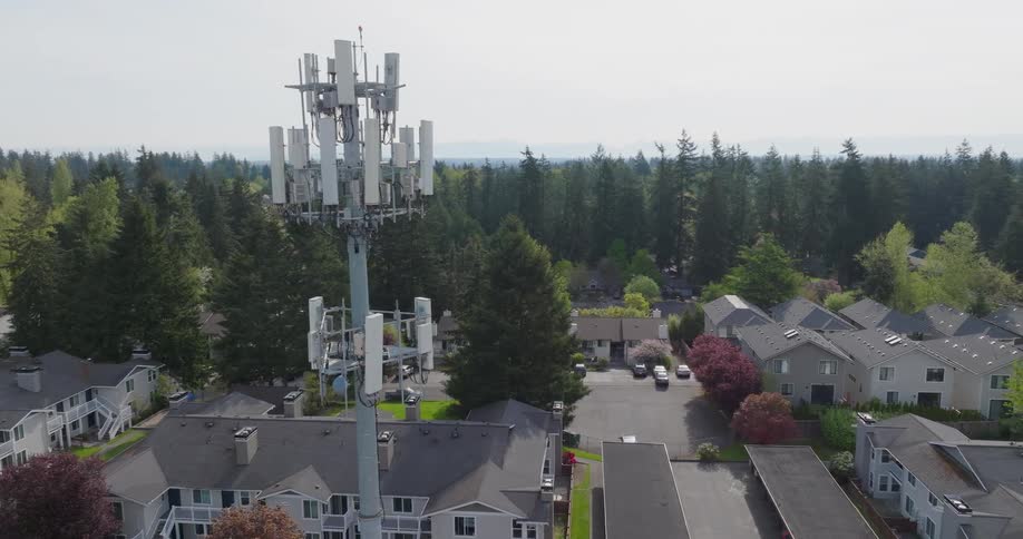 A 5G tower stands near a neighborhood of homes and apartment buildings in a quiet suburb
